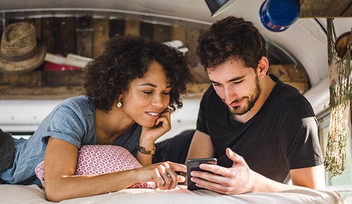 Homme profitant d'un repas en regardant le téléphone portable qui lance Norton 360 Standard.