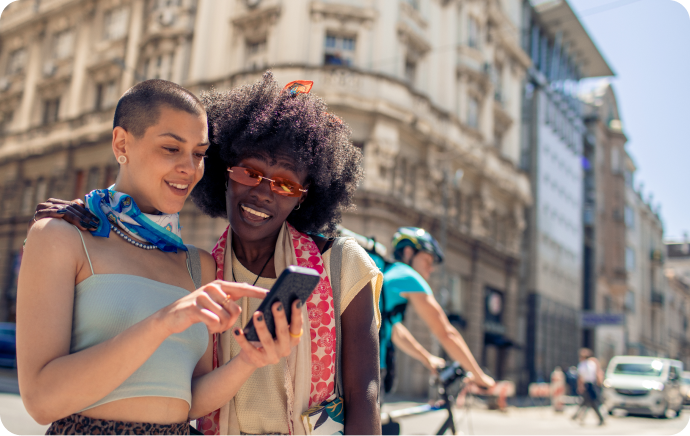 Deux femmes souriant et regardant un téléphone ensemble